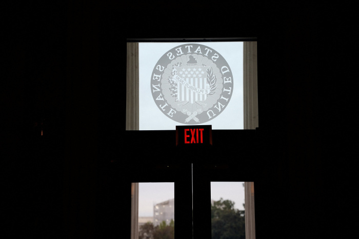 An exit sign illuminated above a door with the United States Senate seal.