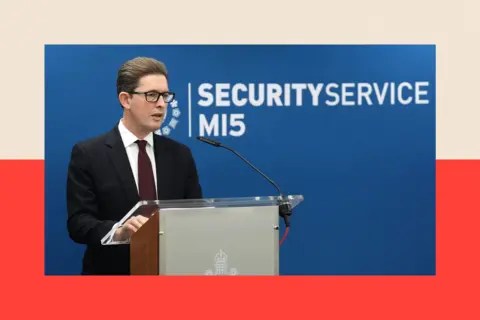 PA Ken McCallum standing at a podium