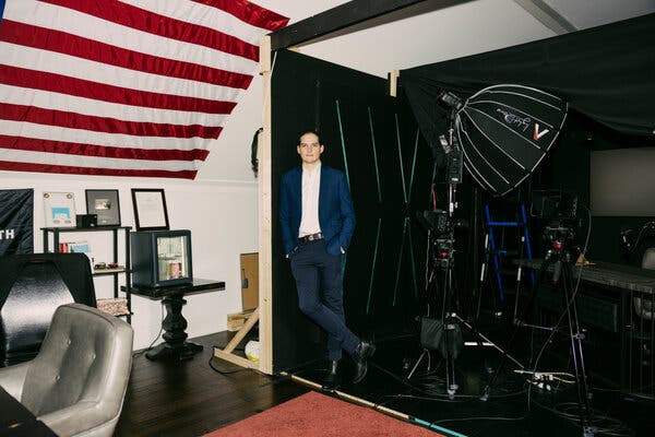 Robby Starbuck stands against a wall of a home studio. 