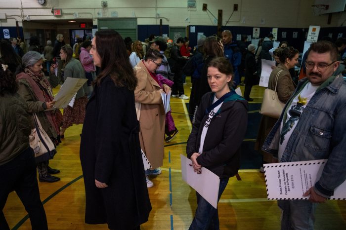 Voters in Brooklyn holding ballot privacy sleeves at a polling station.