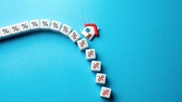 Illustration of a toy house falling down a slope of percentage blocks, representing high interest rates and falling property values.