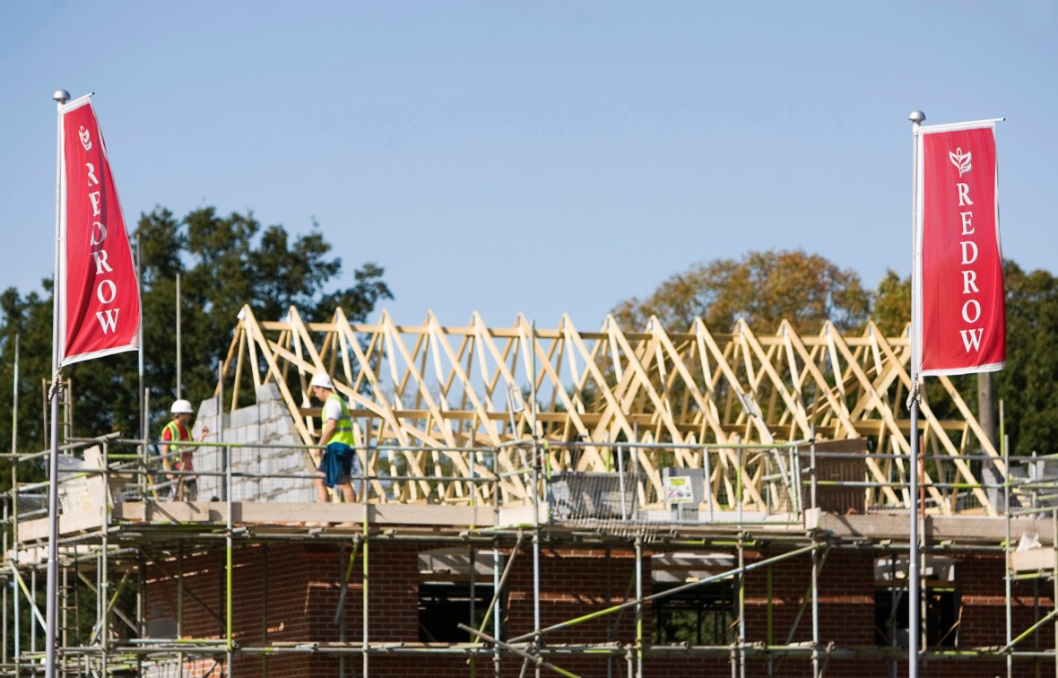 Builders working on a Redrow housing development roof.