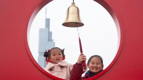 NurPhoto via Getty Images Two young girls ring the New Year bell on the city wall of Nanjing on the first day of the Chinese Lunar New Year in Nanjing, China, on February 17, 2026.