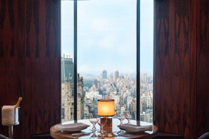 Dining room table set for two, with a view of a city skyline.