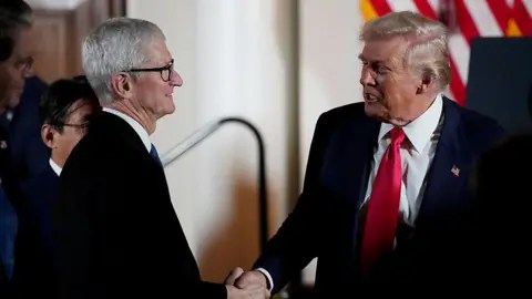 Getty Images US President Donald Trump wearing a suit and red tie shakes hands with Apple CEO Tim Cook who also wears a dark suit, during a meeting with business leaders at the US Ambassador's Residence on 28 October 2025 in Tokyo, Japan.