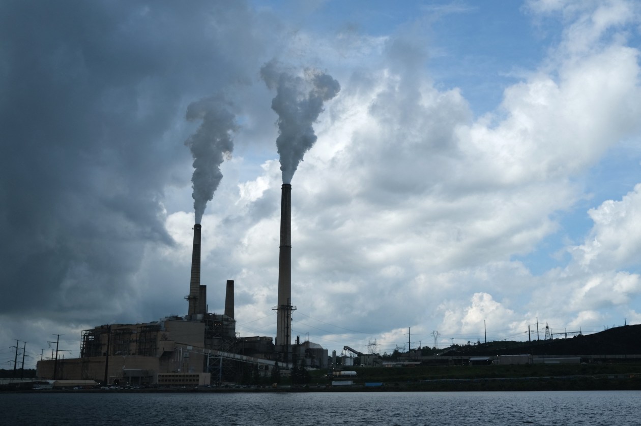 The Mount Storm coal-fired power station, with two smoking chimneys, seen from across a body of water.