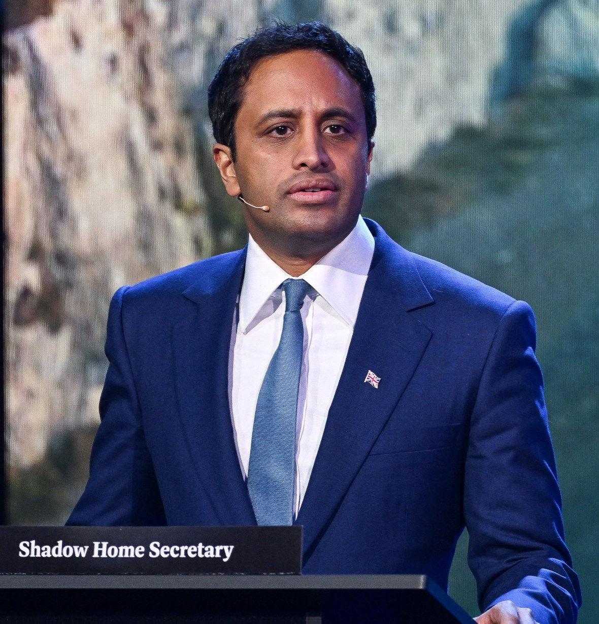 Zia Yusuf speaking at a podium labeled "Shadow Home Secretary."