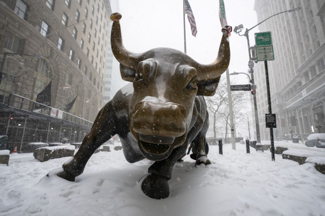 People visit the Wall Street Bull as snow falls in the Financial District on January 25, in New York.
