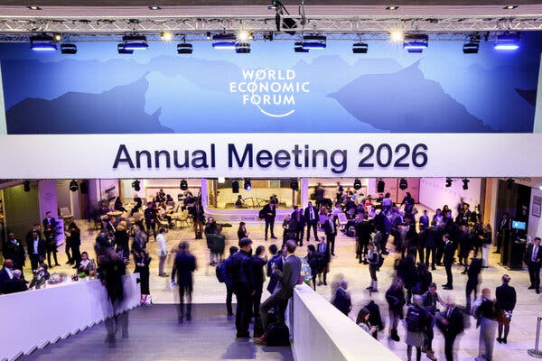 People mingle in a large event hall. A prominent banner reads World Economic Forum Annual Meeting 2026.