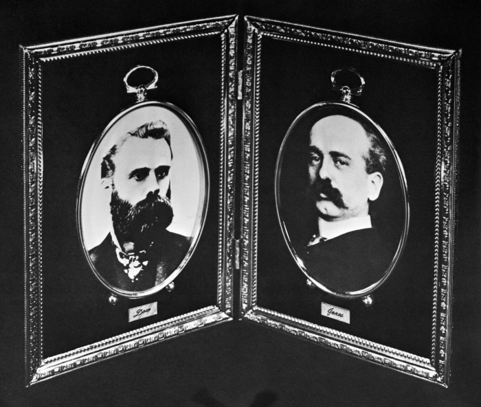 Black-and-white portraits of Charles H. Dow with a beard and Edward T. Jones with a mustache, founders of Dow Jones and Company.