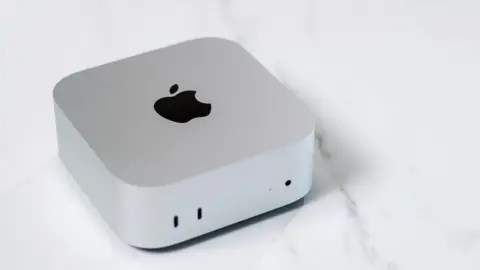 Getty Images A matte, silver-coloured cube with rounded corners and a black Apple logo sits on a white marble countertop.