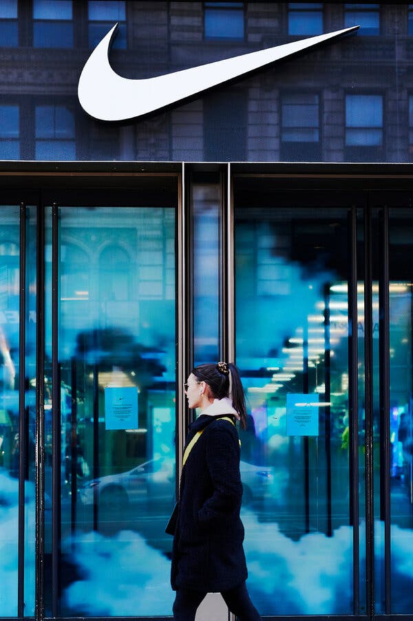 A person walks in front of a Nike store with glass doors.