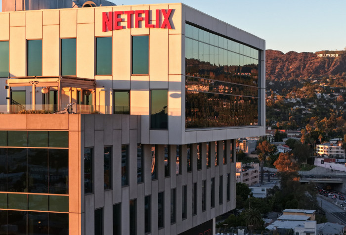 Aerial view of the Netflix logo on a building with the Hollywood sign in the distance.